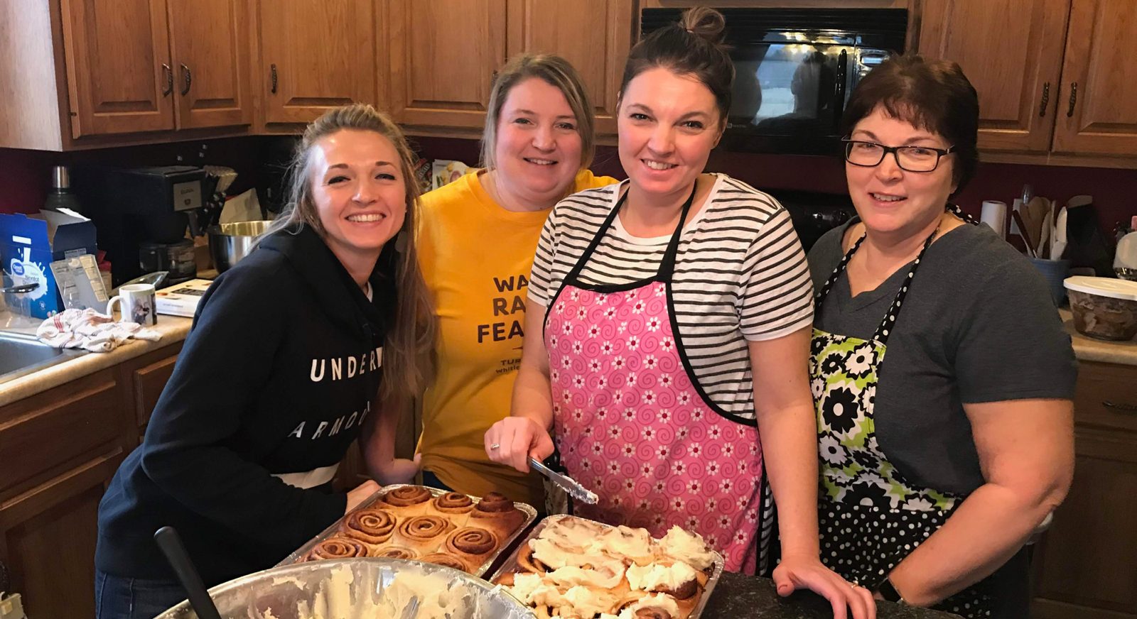 The Roly Rolls family together in the kitchen, frosting trays of cinnamon rolls